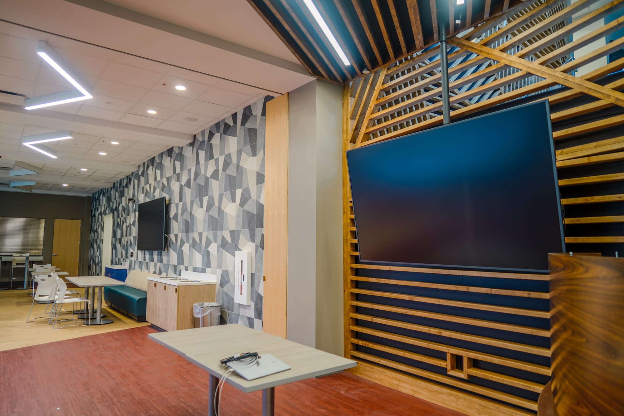 Media lounge with wood-slat feature wall and large-format display, a university student center