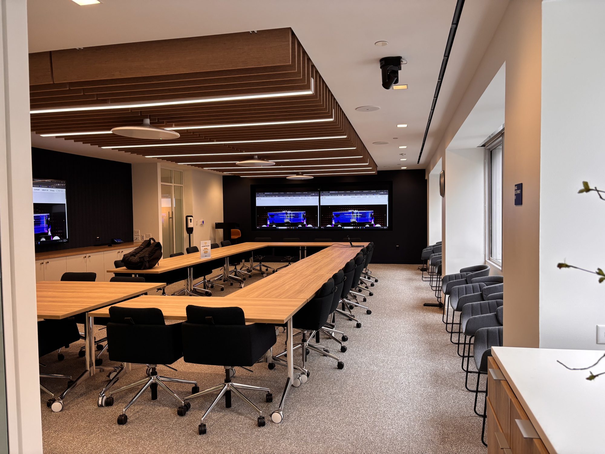 Executive boardroom with dual displays and a wood-slat ceiling